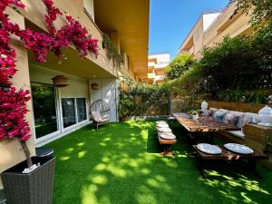 a garden with a table and a couch on the grass at BASTINAZO ALOHADREAM - PREMIUM - Dúplex Lujo Recién Reformado con Jardín, Piscina, Parking, Aire Acondicionado - Los Caños de Meca - 50m playa in Los Caños de Meca