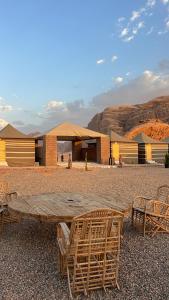 a wooden table and chairs in front of a building at Quiet Night Camp Rum in Wadi Rum