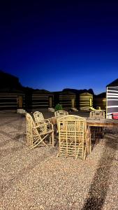 a group of chairs and a wooden table with a table and chairs at Quiet Night Camp Rum in Wadi Rum