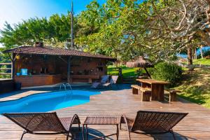 a pool with chairs and a table and a wooden deck at Vale do Lago - Casa de Campo e Eventos in Vila Velha