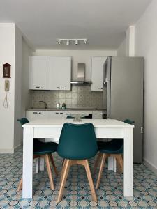 cocina con mesa blanca y 2 sillas verdes en Casa Smeraldo, en Cavo