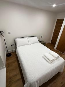 een slaapkamer met een wit bed met twee handdoeken erop bij Room Imperial in Londen