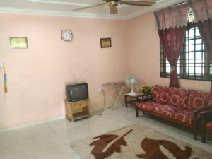 a living room with a red couch and a tv at Z&R HOMESTAY in Kota Bharu