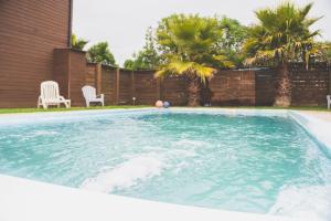 a swimming pool in a yard with two chairs at Cabañas Entremar in Pichilemu