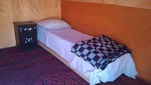 メルズーガにあるDesert Camel Trekのナイトスタンド付きの客室の小さなベッド1台