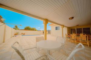 a patio with a white table and chairs at Pool Home Near Palm Beach Plaza – Sleeps 13 in Saliña Cerca