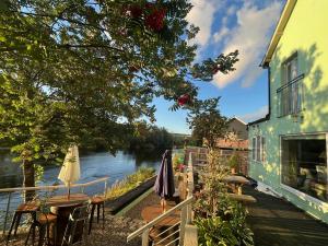 a patio with tables and umbrellas next to a river at By the River in Glasbury