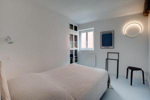 a white bedroom with a bed and a stool at Madeleine Bleue - Heart of Toulouse - Air conditioning, WiFi in Toulouse