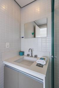 a white bathroom with a sink and a mirror at Belo Studio Varandas - Vila Mariana | Delfhy in Sao Paulo