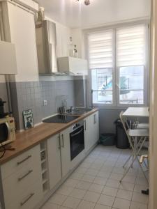 ラ・ガレンヌ・コロンブにあるLe 2piéces parfait pour votre séjour !の白いキャビネットとシンクとテーブルのあるキッチン