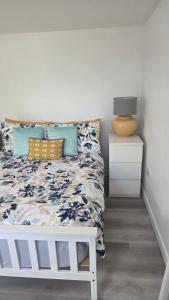 a bedroom with a white bed with blue and yellow pillows at The Little Cabin in St Ives