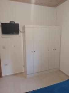 a room with white cabinets and a tv on the wall at Sítio Jabuticabeira in Santo Antônio do Pinhal