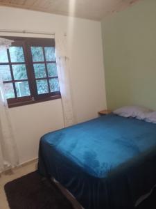 a bedroom with a blue bed and a window at Sítio Jabuticabeira in Santo Antônio do Pinhal