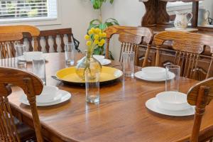 a wooden table with plates and a vase of flowers on it at Magnolia Retreat in Hattiesburg