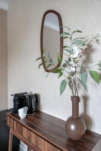 eine Vase mit Blumen auf einem Tisch mit einem Spiegel in der Unterkunft Private Room & Study-friendly, University Tilburg in Tilburg