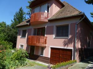 ein rosafarbenes Haus mit einem Balkon und einer Garage in der Unterkunft Liget Szálláshely in Berettyóújfalu