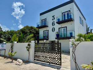 a white building with blue windows and a gate at 360 Suites - Seaside 6Bedroom Retreat in Caye Caulker