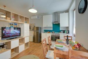 Una cocina y un comedor con una mesa y un televisor. en Vicky Loft Morgnaga - Happy Rentals, en Gardone Riviera