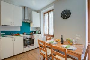 Una cocina con una mesa y un reloj en la pared. en Vicky Loft Morgnaga - Happy Rentals, en Gardone Riviera