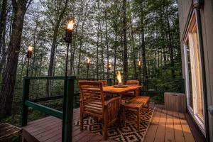 a porch with a table and chairs on a deck with trees at Finley Lodge in Bartlett