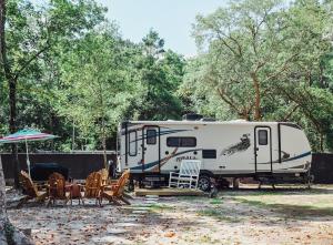 an rv parked next to a table and chairs at Nicevilles' Hidden Backyard Camper in Niceville