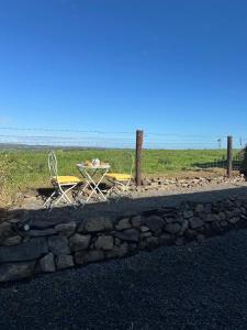 a table and chairs sitting next to a stone wall at Country Cosy Cottage in Bailieborough