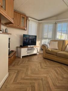 a living room with a television and a couch at marine getaways caravan hire winchester in Rhyl