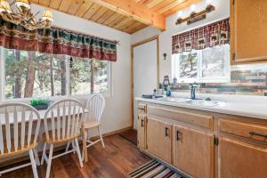 a kitchen with a sink and a table and chairs at Big Bear Cabin with Treetop Views 3 Decks Arcade Game, Fireplace, BBQ, WIFI in Big Bear City