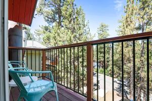 a blue chair sitting on a balcony with trees at Big Bear Cabin with Treetop Views 3 Decks Arcade Game, Fireplace, BBQ, WIFI in Big Bear City