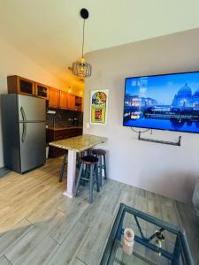 a kitchen with a table and a tv on the wall at Paradise stay beach walk and dinning in Jacó