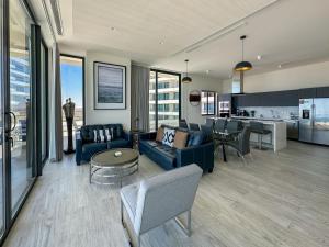 a living room with a blue couch and a kitchen at Waves & Views Luxury 3BR Oceanfront Condo in Puerto Peñasco