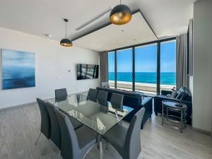 a dining room with a glass table and chairs and the ocean at Waves & Views Luxury 3BR Oceanfront Condo in Puerto Peñasco