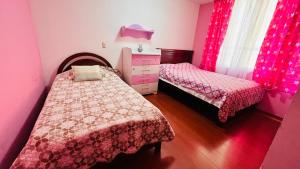 two beds in a room with pink walls at Cómodo y hermoso apartamento cerca de supermaxi in Loja