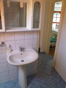 a bathroom with a white sink and a mirror at Liget Szálláshely in Berettyóújfalu