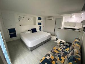 a bedroom with a large white bed and a kitchen at La Casa Blanca Hotel in Buenaventura