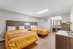 a hotel room with two beds and a sink at Guest Inn Rogers in Rogers