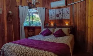 a bedroom with a bed with purple sheets and a window at Chalé Temático em Pipa de Vinho - Parada da Pipa Chalés in Canela