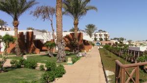 Romantic Sea View Villa at V Hotel Sharm El-Sheikh, Egypt في شرم الشيخ: ممشى من خلال حديقة بها نخل ومباني