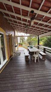 a wooden deck with benches and a table on it at Casa Completa/Condo Sensacional in Mangaratiba