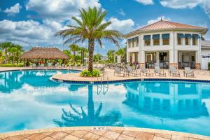 Una piscina tipo resort con sillas y una palmera. en Storey Lake condos by Une Homes, en Kissimmee