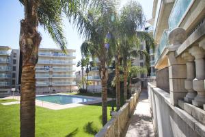 un patio con palmeras y una piscina en Ancora Planetcostadorada, en Salou
