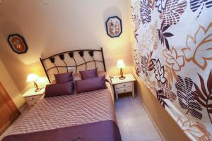 a small bedroom with a bed with purple pillows at Carlos V Planetcostadorada in Salou