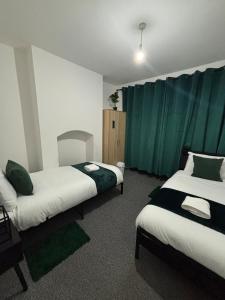 two beds in a room with green curtains at 3bd in leicester near M1 - city - contractors in Leicester