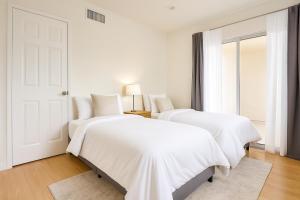 マリブにあるMalibu Woods & Waves - 2 Bedroomのドア付きの白い部屋のベッド2台