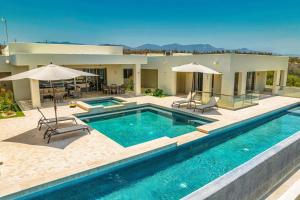 a pool with chairs and umbrellas in front of a house at Casa Ali East Cape Luxury Villa by The Agency Baja in El Cardonal