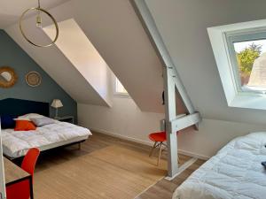 a attic bedroom with two beds and a window at La Maison Bleue à 40m de la plage in La Turballe