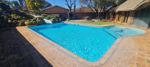 a swimming pool with blue water in a yard at Apollo Guest House in Mahikeng