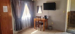 a room with a table and a television and a desk at Apollo Guest House in Mahikeng