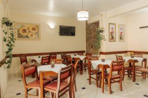 a dining room with tables and chairs and a tv at Pousada Florescer in Ubatuba