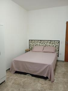 a bedroom with a white bed with pink pillows at Marta's house in Peruíbe +11 photos